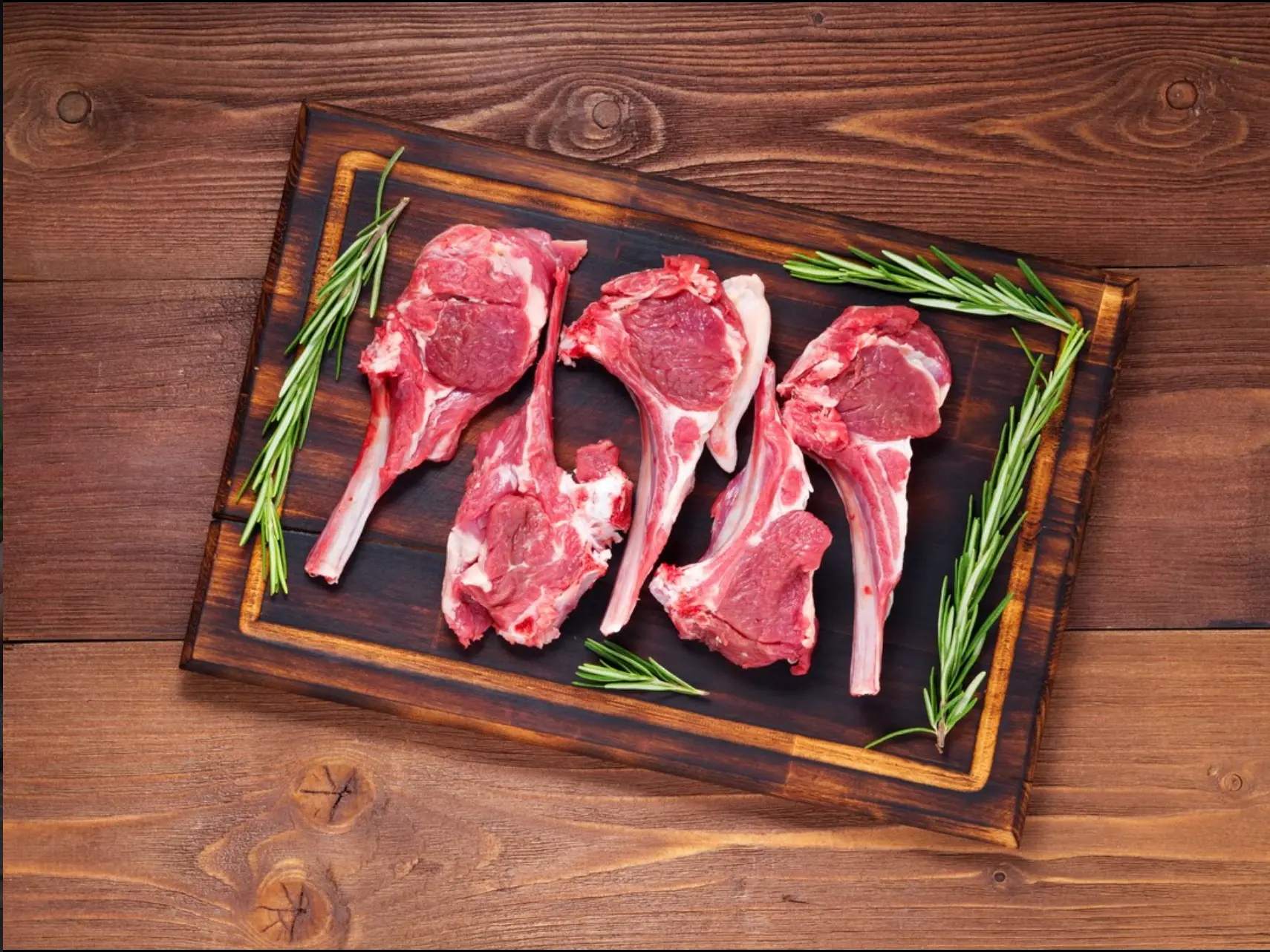 Fresh lamb cutlets with rosemary on a wooden board